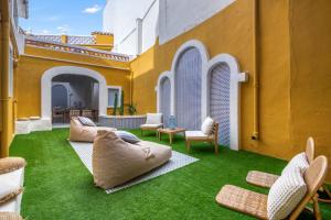 a patio with green grass and chairs and a building at La Bonita de Pego in Pego