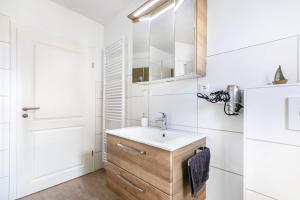 a white bathroom with a sink and a refrigerator at Ferienhus-voern-Diek in Kaiser Wilhelm Koog +20 photos