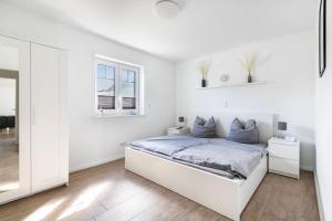 a white bedroom with a bed and two windows at Ferienhus-voern-Diek in Kaiser Wilhelm Koog
