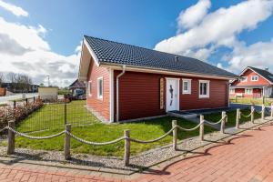a small red house with a fence around it at Ferienhus-voern-Diek in Kaiser Wilhelm Koog