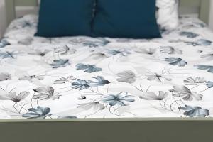 a bed with a white sheet with blue flowers on it at Charming House Secret Rose in Flor da Rosa