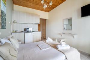 a bedroom with a white bed and a kitchen at Nontas Home 33 in Kalamitsi