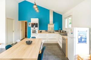 a kitchen with a wooden table and a refrigerator at Maison Cosy avec Piscine in Tarnos