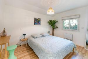 a bedroom with a bed and a table and a window at Maison Cosy avec Piscine in Tarnos