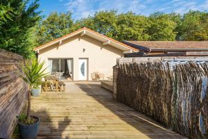 a house with a fence and a wooden walkway at Maison Cosy avec Piscine in Tarnos