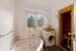 ein Badezimmer mit Badewanne und Waschmaschine in der Unterkunft Badeuferhaus in Kosel