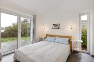 ein weißes Schlafzimmer mit einem Bett und einem großen Fenster in der Unterkunft Badeuferhaus in Kosel