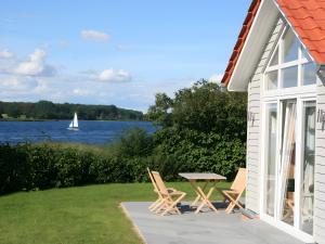 eine Terrasse mit Stühlen, einem Tisch und einem Segelboot in der Unterkunft Badeuferhaus in Kosel
