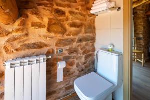 a bathroom with a toilet and a stone wall at Casa Tunino in Monforte de Lemos +30 photos