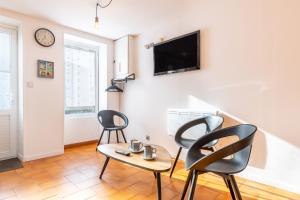 a living room with two chairs and a table and a tv at Maison traditionnelle au centre in Les Sables-d'Olonne