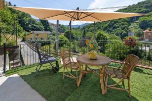 a table and chairs with an umbrella on a balcony at Maison Nature e Relax Rubino in Osiglia +20 photos