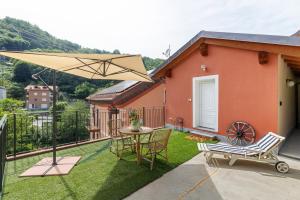 a patio with a table and chairs and an umbrella at Maison Nature e Relax Rubino in Osiglia
