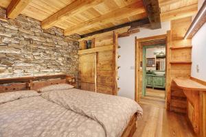 ein Schlafzimmer mit einem Bett und einer Steinwand in der Unterkunft Chalet Brenand in Rhêmes-Notre-Dame