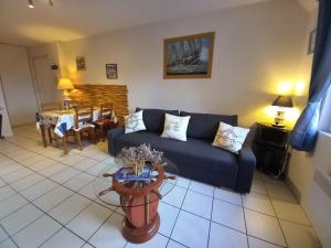 a living room with a blue couch and a table at Côte fleurie -Le Cottage D'honfleur in Honfleur