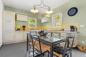 a kitchen with a dining table and a clock on the wall at La Cabri 5 Chambres Piscine in Cabris