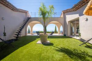 a patio with a palm tree in a pot on the grass at La Cabri 5 Chambres Piscine in Cabris