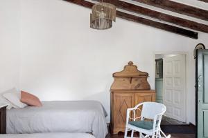 a white bedroom with a bed and a chair at Casa Julia in Las Lagunas