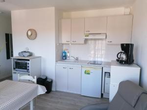a small kitchen with white cabinets and a table at Les Alisiers in Eugénie-les-Bains
