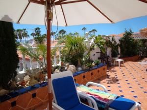 a patio with chairs and an umbrella and palm trees at Romantic Villa with private Pool in Adeje