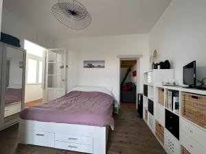 a white bedroom with a bed and a television at Appartement bord de plage-Arcachon in Arcachon
