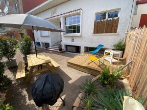 a patio with a table and chairs and an umbrella at Appartement bord de plage-Arcachon in Arcachon