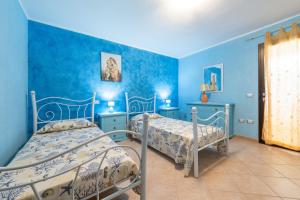 two beds in a room with blue walls at Villetta Delfino in Sìnnai