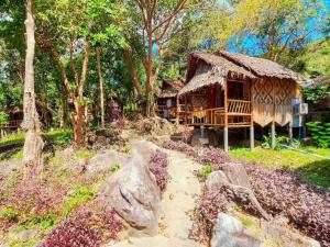 a house with a thatch roof in a forest at Phuphaya Seaview Adults Only in Phi Phi Islands