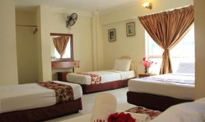 a hotel room with two beds and a window at Sun Inns Setiawan in Sitiawan