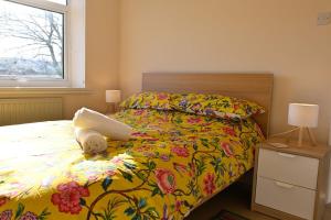 a bedroom with a bed with a colorful comforter and a window at 7 Western Hill in Frosterley