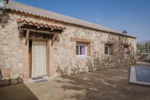 a stone building with a window and a courtyard at El Cauce in Navaluenga