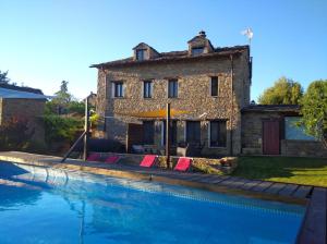 a house and a swimming pool in front of a building at A Boira Rural in Osia