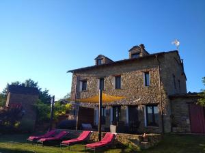 a group of chairs and an umbrella in front of a building at A Boira Rural in Osia