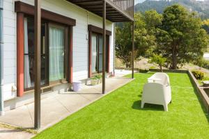 a patio with a white chair and a table on grass at kaze no ne in Takachiho +21 photos