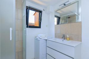 a white bathroom with a sink and a mirror at Loc Ty Home in Soustons +17 photos