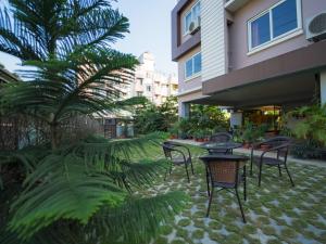 a patio with chairs and tables and a palm tree at Happy Villa Guest House in Guwahati