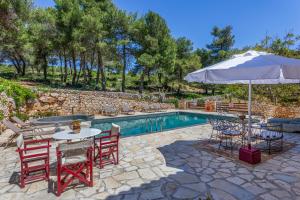 a patio with a table and chairs and an umbrella at Villa Ira in Agios Leon