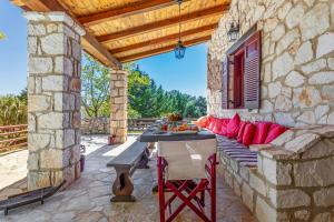 an outdoor patio with a table and red pillows at Villa Ira in Agios Leon