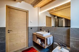 a bathroom with two sinks and a wooden door at Krämerhof Apt Aferer Geisler in Rodengo +20 photos