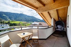 a balcony with a table and chairs and mountains at Krämerhof Apt Aferer Geisler in Rodengo