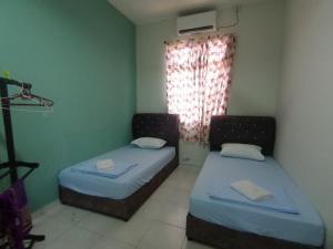 two beds in a small room with a window at Promenade Homestay 2 in Kampong Sura Masjid