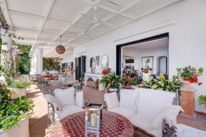 a patio with white chairs and tables and flowers at Villa Bella Vista in Capri