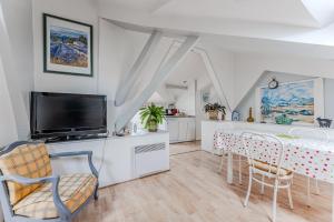 a living room with a table with chairs and a tv at Appartement de maitre traversant in La Teste-de-Buch