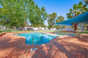 a swimming pool with a canopy and trees at Rivergardens Holiday Park Mildura in Gol Gol