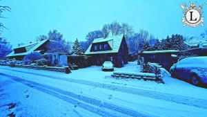 a house covered in snow with a car parked in the driveway at Landhaus Ferien Ostsee in Sterup