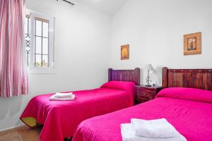two beds in a room with pink sheets at Chalet Villa Ariza in Cádiz +19 photos
