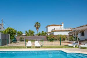 a swimming pool with two lounge chairs and a house at Chalet Villa Ariza in Cádiz