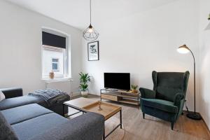 a living room with a couch and two chairs and a tv at Ferienwohnung Finsterwalde 2 in Finsterwalde