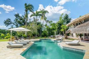 a swimming pool with lounge chairs and an umbrella at Ocean View Villa, Pool, BBQ, Jacuzzi, Staff Incl in Cajuiles