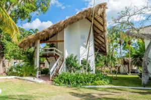 a white house with a thatched roof at Ocean View Villa, Pool, BBQ, Jacuzzi, Staff Incl in Cajuiles