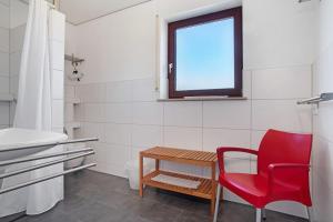 a red chair and a table in a bathroom at Gästehaus Heinemann - Og5 in Langenargen +22 photos